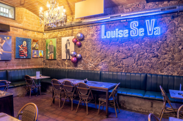 Interior de Louise Se Va con neón y pósters de conciertos